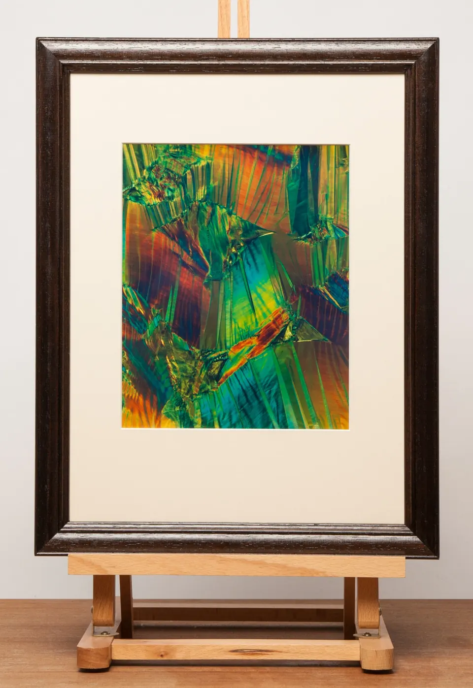 Gerahmtes abstraktes Bild mit grünen und orangefarbenen Bahnen und roten und blauen Akzenten.