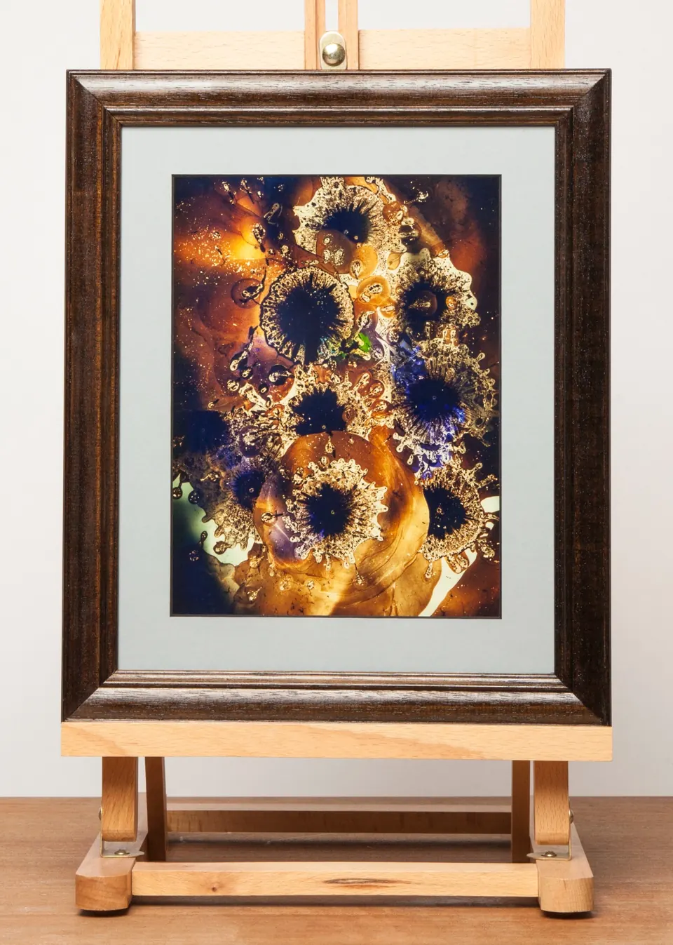 Gerahmtes abstraktes Bild mit goldenen kreisförmigen Strukturen und dunkelvioletten Flächen.