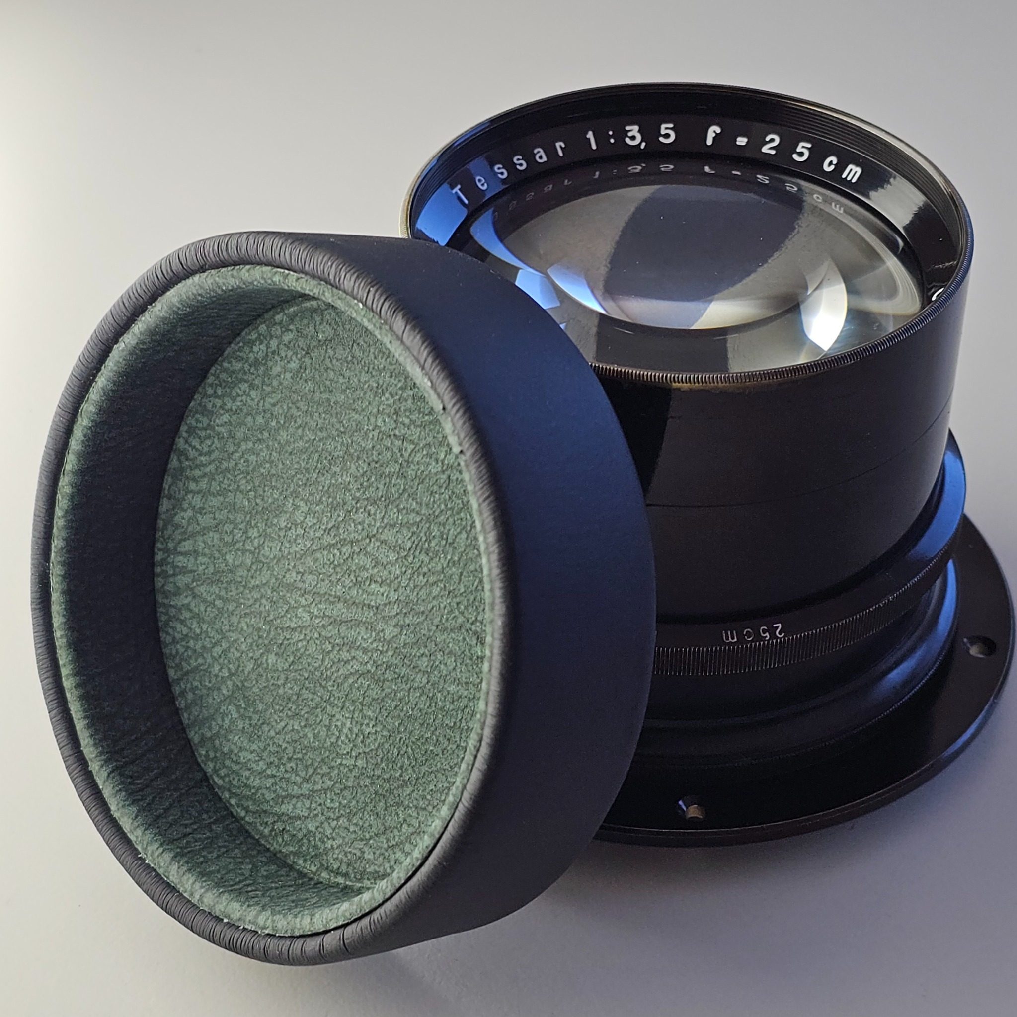 Tessar 25 cm f/3,5 neben dem Lederdeckel mit grüner Rauleder-Innenauskleidung.